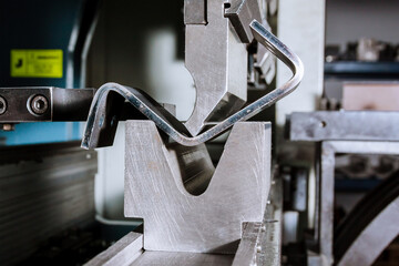 Sheet metal bending on a hydraulic bending machine. Metal part after bending.