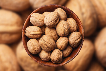 Walnuts background. Walnuts in wooden bowl. Whole nuts in shells in round container with empty copy space for graphic design text. Healthy food ingredient texture.