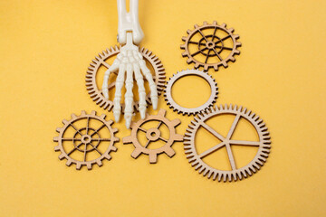 Skeleton hand over  gearwheel. Death and industry concept