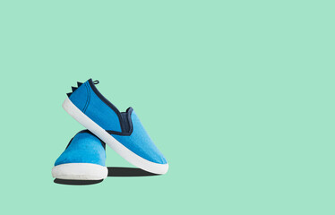 Blue sneakers on a green pastel background. Baby shoe concept. Dressing shoes for kindergarten, for...