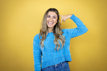 Pretty blonde woman with long hair standing over yellow background smiling and thinking with her fingers on her head that she has an idea.