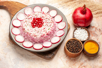 Side view of tasty salad on wooden cutting board different spices and pomegranate on mixed color background