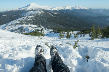 legs of the traveler in hiking boots with snow gaiters in the snowy mountains 