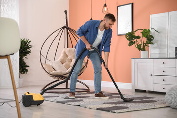 Young man using vacuum cleaner at home