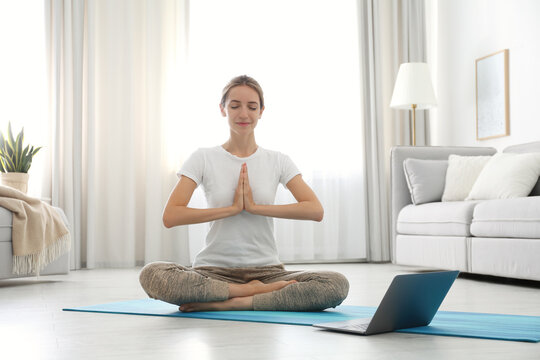 Woman having online video class via laptop at home. Distance yoga course during coronavirus pandemic