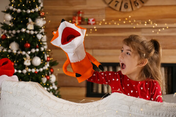 Cute little girl performing puppet show at home