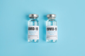 Vials with coronavirus vaccine on light blue background, flat lay