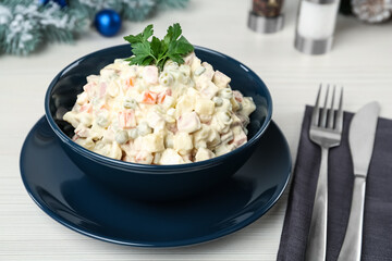 Traditional russian salad Olivier served on white wooden table