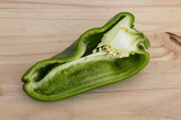 Green chili cut in half, showing seeds on wooden background