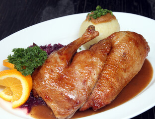 Roasted half duck with red cabbage, potato dumpling, orange sauce, parsley and orange garnish