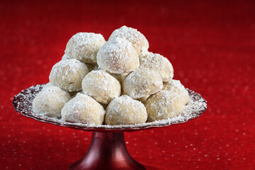 Holiday treat, Russian Teacakes stacked on a red cake plate, on a red velvet tablecloth
