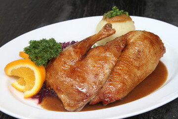 Roasted half duck with red cabbage, potato dumpling, orange sauce, parsley and orange garnish