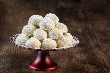Holiday treat, Russian Teacakes stacked on a red cake plate on a rustic wood table
