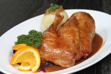 Roasted half duck with red cabbage, potato dumpling, orange sauce, parsley and orange garnish