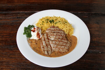 Pork escalope hunter style in creamy sauce served with spaetzle and whipped cream