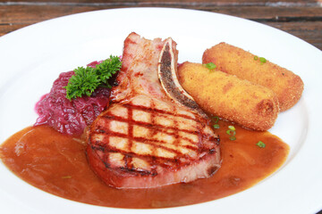 Smoked pork chop with potato croquettes, red cabbage and gravy. German dish