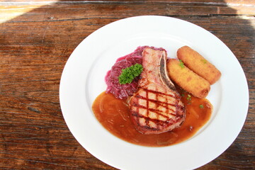 Smoked pork chop with potato croquettes, red cabbage and gravy. German dish