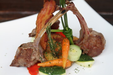 Lamb chops served with crispy bacon and vegetables