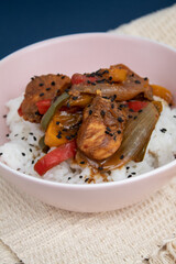 Bowl with cooked rice and plaid chicken decorated with black sesame with background