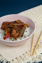 Bowl with cooked rice and plaid chicken decorated with black sesame with background