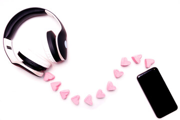 Black and white headphones with a smartphone on a white background, a wire in the form of marshmallows hearts. Listen to your heart - Valentine's Day. Copy space.