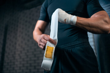 athletic boxer man bandage hand and preparing for training or fighting in gym