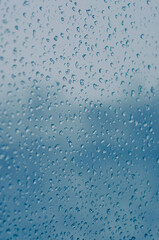 Melting snow on the glass, drops of water condensation on the window, and transparent glass of the window in cold winter, winter landscape outside the window, close-up.