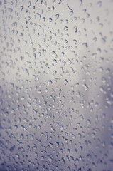 Melting snow on the glass, drops of water condensation on the window, and transparent glass of the window in cold winter, winter landscape outside the window, close-up.