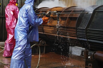 Worker use high pressure water jet to cleaning splashing the dirt of tube bundle in industrial areas, chemical products or oil and gas plants.