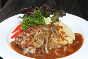 Pork steak with potato mash, onion jus and mixed greens