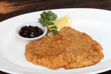 Pork Schnitzel Vienna style served with cranberry jam and lemon. Bread crumbed pork escalope.