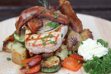 Pork steak with crispy bacon, served on grilled vegetables and horseradish cream