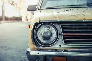 Close up and front view shot with copy space of chrome grill and front light of yellow retro car in grunge condition with rust and dirt shows beautiful detail and old day american style design