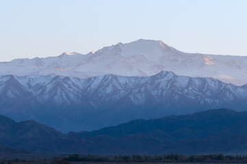 Naklejka premium Low contrast photo of mountain range with snow peaks in different shades of blue and cyan. Flat contrast scene with negative space available for text. 