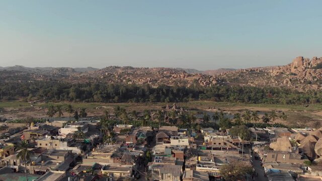 Hampi town's edge with old buildings contrasting with the rocky landscape in Karnataka, India - Aerial Panoramic shot