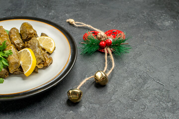 bottom half view stuffed grape leaves on white plate and xmas pendant on dark background with copy space