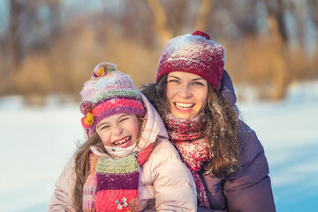 Fototapeta premium Little girl and her mother playing outdoors at sunny winter day. Active winter holydays concept.