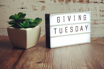 Giving Tuesday word in light box on wooden background