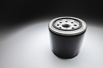 Black new oil filter in contrasting light on a black and white background. Wide angle