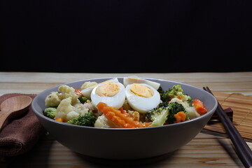 Fried and stirred rice topping with steamed egg and mixed vegetable serving on the plate. Famous traditional vegetarian menu in Asia restaurant. High vitamin and fiber food.