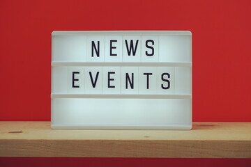 News Events word in light box on red and wooden shelves background
