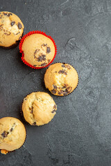 Vertical view of freshly baked small cupcakes with chocolates on dark background