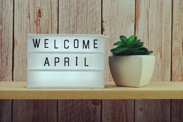 Welcome April word in light box on wooden shelves background