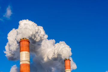 Puffs of smoke and steam from the chimneys of the CHP plant against the blue sky in Moscow