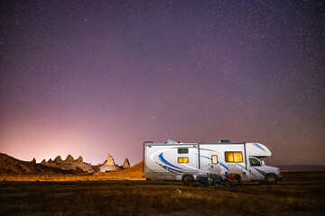 Camper rests by RV and illuminated tufa spires - obrazy, fototapety, plakaty