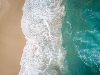 Aerial drone photo of beach in Australia with Pacific Ocean waves crashing in and golden sand beaches with blue water © Orion Media Group