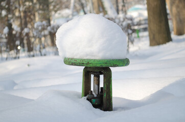 Water faucet for watering the street with a large cap of snow in winter