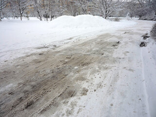 Roadway is covered with a thick layer of dirty loose snow in winter