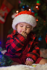 a child in red clothes is sitting waiting for the new year. the concept of celebrating Christmas at midnight. holiday costume