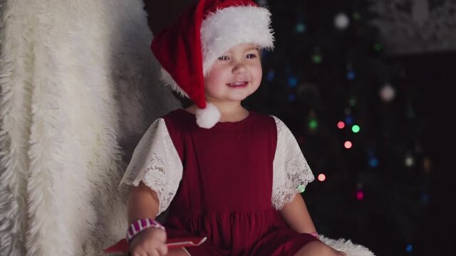 a child in red clothes is sitting waiting for the new year. the concept of celebrating Christmas at midnight. holiday costume. a girl writes a letter to Santa Claus. wish list